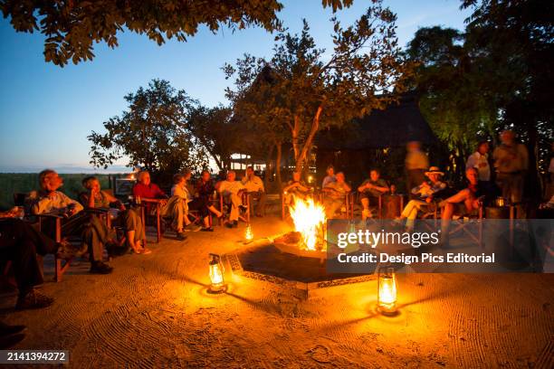 Visitors to the Selinda Reserve enjoy an evening campfire. Selinda Reserve, Botswana.