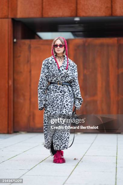 Guest wears a red hat / balaclava, a black and white trench coat with leopard patterns, a black leather bag, red sunglasses, red tights, red kitten...
