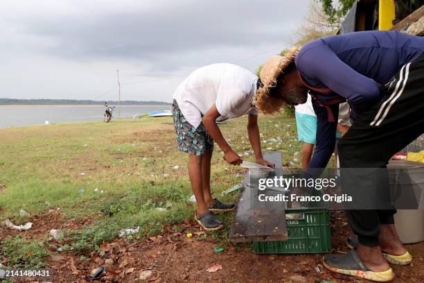 Men clean fish at the port on the Orinoco River on April 05, 2024 in Puerto Carreño, Colombia. Puerto Carreño is the departmental capital city, and a...