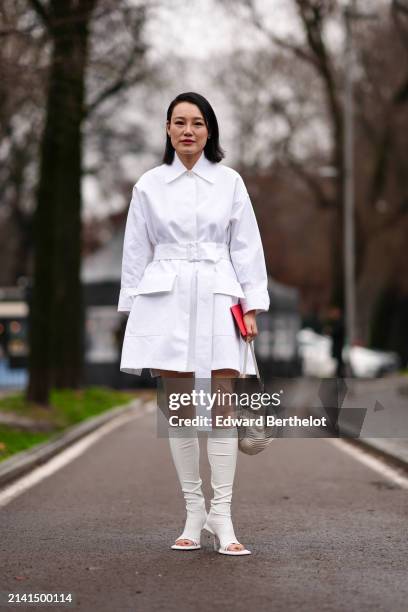 Guest wears a whit shirt dress, a beige leather bag, white / beige leather high heels, outside Tod's, during the Milan Fashion Week - Womenswear...