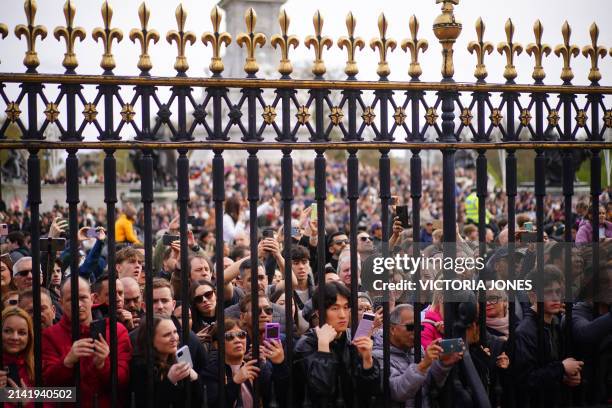Members the public gather outside the gates of Buckingham Palace in London on April 8 to watch a special Changing of the Guard ceremony with of...