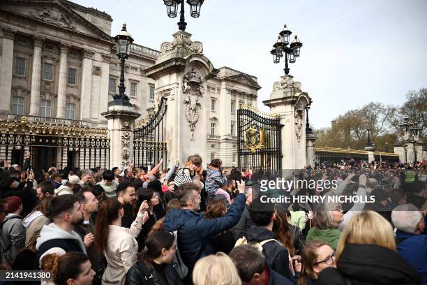 Members the public gather outside the gates of Buckingham Palace in London on April 8 to watch a special Changing of the Guard ceremony with of...