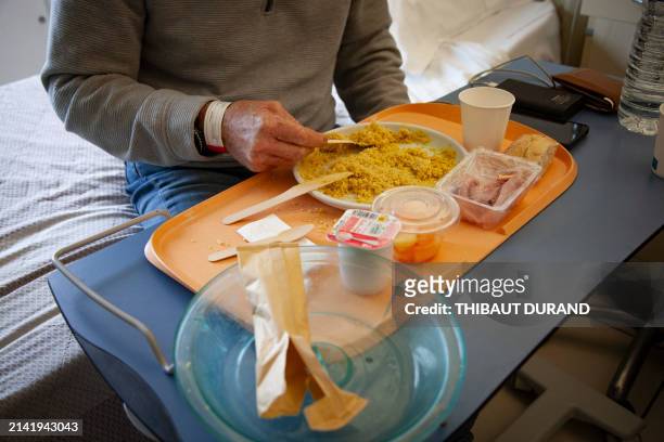An elderly man, hospitalized for a heart attack, eats his meal in his room, France, Castelnau-le-Lez, April 6, 2024. Un homme age, hospitalise pour...