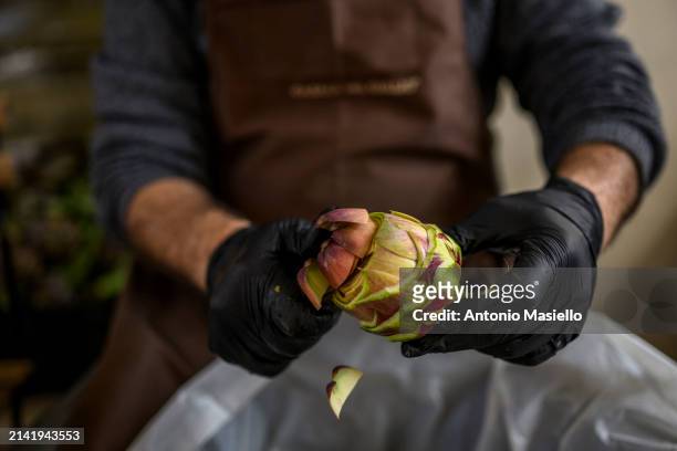Man cuts and cleans fresh Roman artichokes in a restaurant at the Jewish quarter during the inauguration of the Festival of the Roman Artichoke , on...