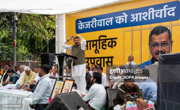 Leader Sanjay Singh speaks to protesters in the background is a billboard depicting Delhi chief Minister Arvind Kejriwal behind bars, a symbolic...