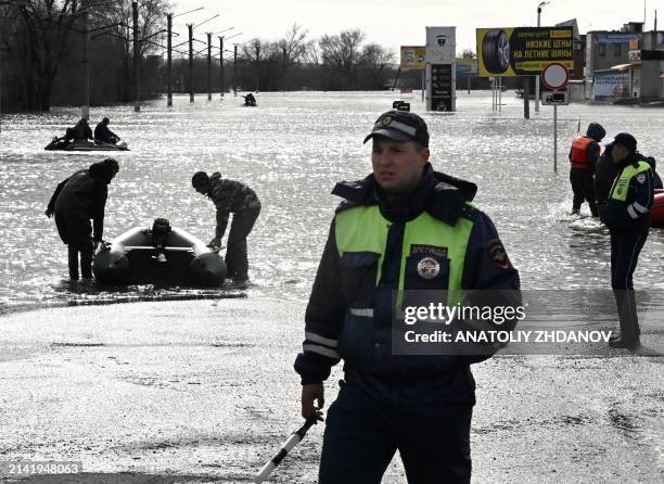 Traffic police officers stand on a flooded street as rescuers on inflatable boats evacuate residents of the city of Orsk, Russia's Orenburg region,...