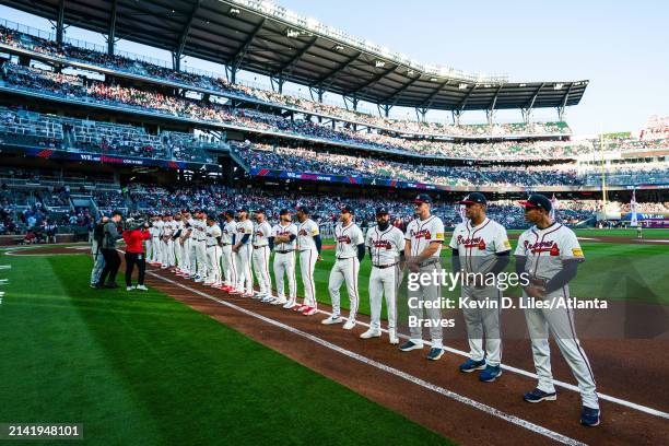 Raisel Iglesias, Jarred Kelenic, Luis Guillorme, Sean Murphy, Eddie Perez and Bobby Magallanes of the Atlanta Braves stand on the field before the...