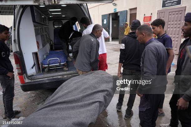 Palestinians transport the body of a victim following Israeli bombardment on al-Bureij camp in the central Gaza Strip on April 8 as the war between...