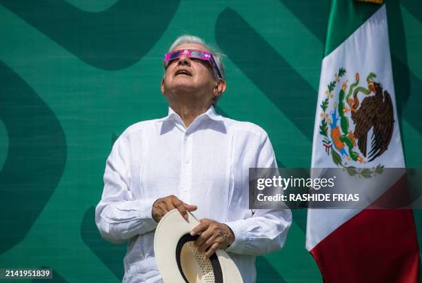 Mexican President Andres Manuel Lopez Obrador wears special sunglasses as he observes a solar eclipse moments before totality, in Mazatlan, Sinaloa...