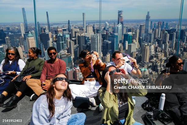 People look toward the sky at the 'Edge at Hudson Yards' observation deck ahead of a total solar eclipse across North America, in New York City on...