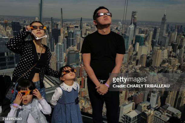 People look toward the sky at the 'Edge at Hudson Yards' observation deck during a solar eclipse across North America, in New York City on April 8,...
