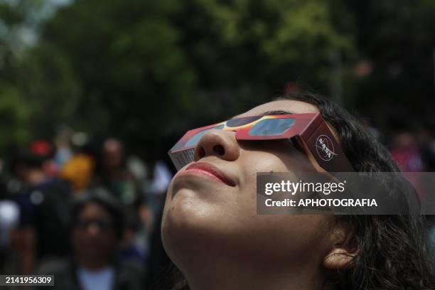 Young woman observes the alignment of the Moon with the Sun during the Partial Solar Eclipse with species glasses at Micro Macro Observatory , on...