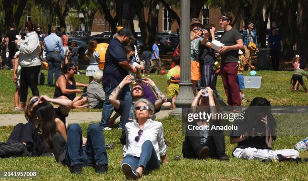 People observe the total solar eclipse through safety glasses at an eclipse watch party at the Orlando Science Center on April 8, 2024 in Orlando,...