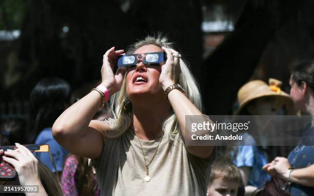 Woman watches the total solar eclipse through safety glasses at an eclipse watch party at the Orlando Science Center on April 8, 2024 in Orlando,...