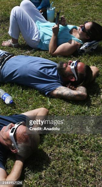 People observe the total solar eclipse through safety glasses at an eclipse watch party at the Orlando Science Center on April 8, 2024 in Orlando,...