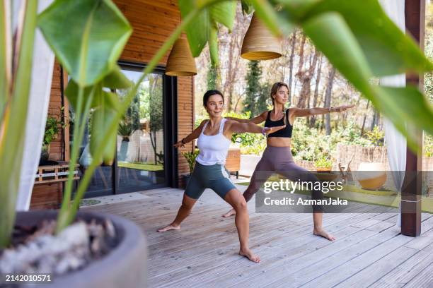 two adult female friends practicing yoga on a charming terrace - yogi stock pictures, royalty-free photos & images