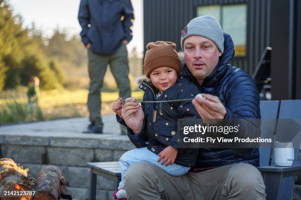 toddler girl roasting marshmallows with her uncle - uncle stock pictures, royalty-free photos & images