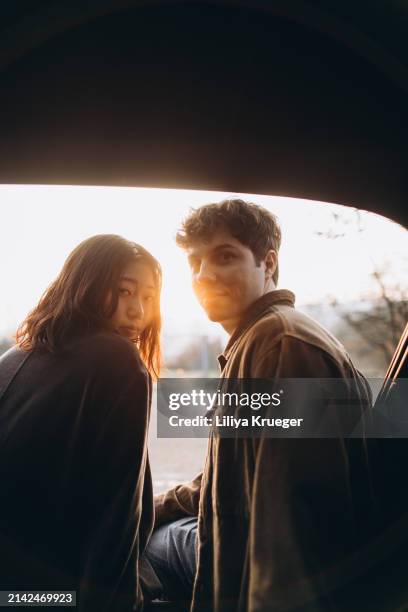 young multi-ethnic couple in the car at the sunset. - ethnic woman driving a car stock pictures, royalty-free photos & images