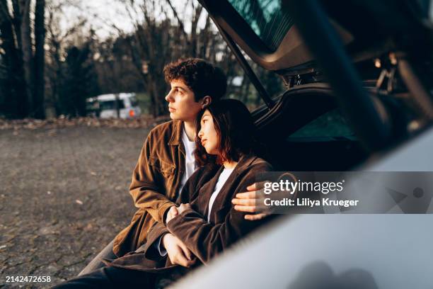 young multi-ethnic couple in the car at the sunset. - ethnic woman driving a car stock pictures, royalty-free photos & images