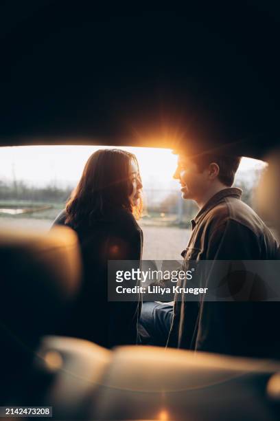 young multi-ethnic couple in the car at the sunset. - ethnic woman driving a car stock pictures, royalty-free photos & images
