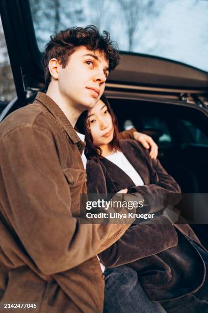 young multi-ethnic couple in the car at the sunset. - ethnic woman driving a car stock pictures, royalty-free photos & images