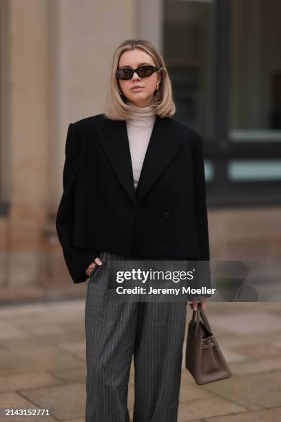 Isabelle Hartmann seen wearing Vehla Eyewear black / brown sunglasses, gold earrings, COS creamy white turtleneck top, Khaite black cropped oversized...