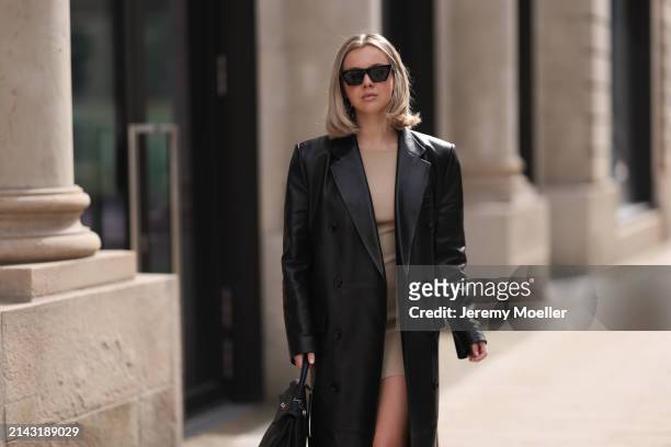 Isabelle Hartmann seen wearing Celine black sunglasses, vintage beige short dress, Magda Butrym black leather long coat and Hermès Kelly black...