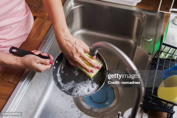 directly above shot of asian woman hands washing crockery and kitchen utensils in kitchen sink. - spugna per le pulizie foto e immagini stock