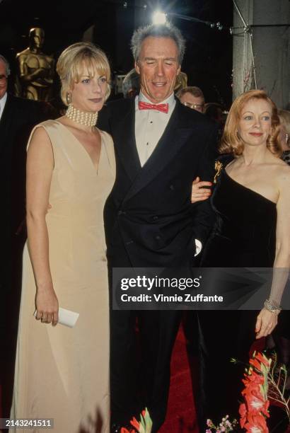 American actress Alison Eastwood, wearing an ivory-coloured evening gown with a pearl choker, with her father, American actor and film director Clint...