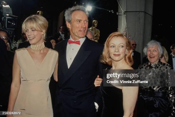 American actress Alison Eastwood, wearing an ivory-coloured evening gown with a pearl choker, with her father, American actor and film director Clint...