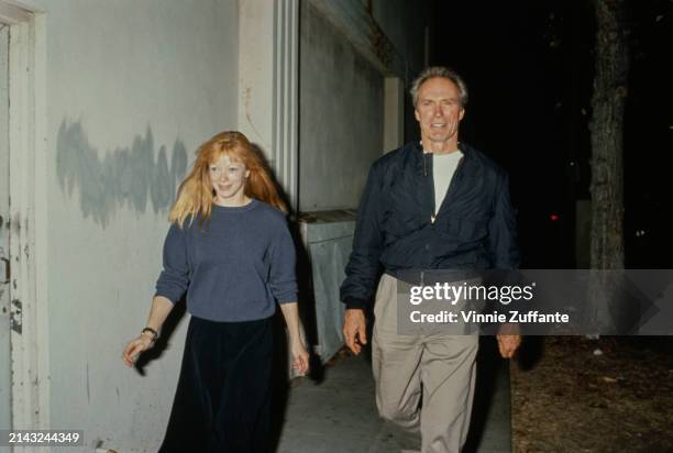 American actress Frances Fisher, wearing a blue sweatshirt with a black skirt, and her partner, American actor and film director Clint Eastwood, who...