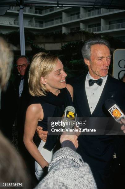 American actress Sharon Stone, wearing a sleeveless black outfit, and American actor and film director Clint Eastwood, who wears a tuxedo and bow...