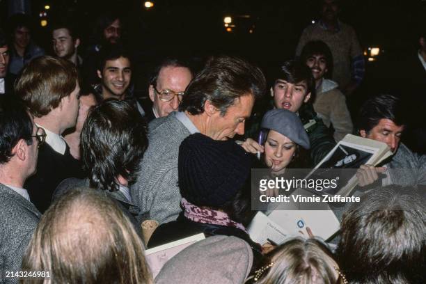 American actor and film director Clint Eastwood, wearing a tweed jacket, signs autographs for fans as he attends a screening of his film 'Honkytonk...