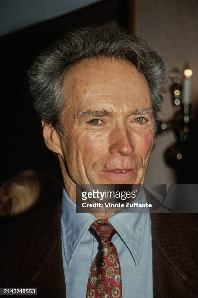 American actor and film director Clint Eastwood, wearing a brown blazer over a light blue shirt and a red patterned tie, attends the 18th Annual LA...