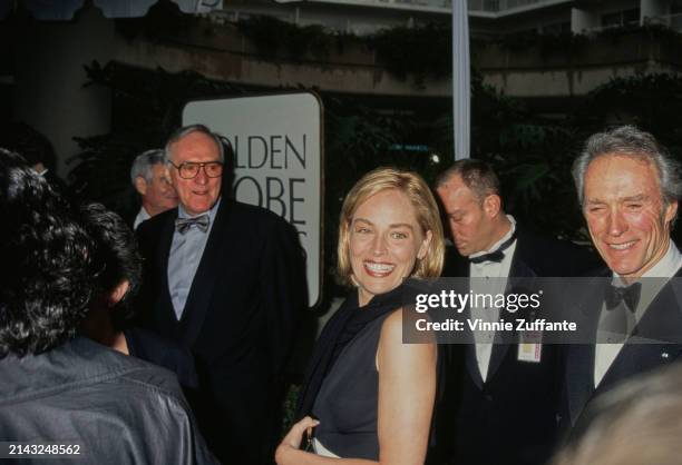 American actress Sharon Stone, wearing a sleeveless black outfit, and American actor and film director Clint Eastwood, who wears a tuxedo and bow...