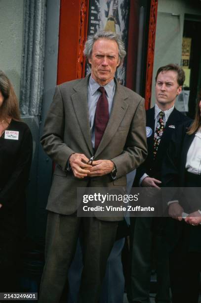 American actor and film director Clint Eastwood, wearing a grey blazer over a grey shirt with a deep red tie, attends the Westwood premiere of 'Ace...