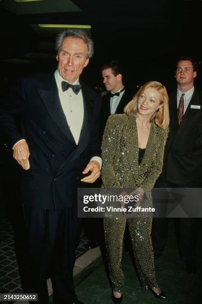 American actor and film director Clint Eastwood, wearing a tuxedo and bow tie, and American actress Frances Fisher, who wears a gold trouser suit,...