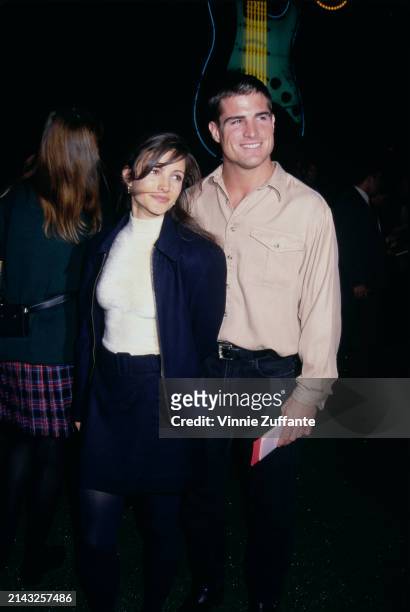 American actress Kristin Davis, wearing a dark blue jacket over a white turtleneck sweater, and American actor George Eads, who wears a beige shirt...