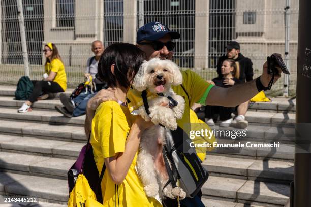 Two people hold their dog while taking a selfie ahead of the non competitive "Arcaplanet Dog Run" at CityLife district on April 06, 2024 in Milan,...