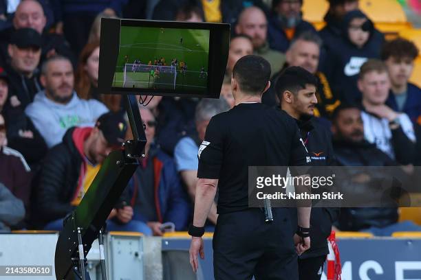 Referee Tony Harrington checks the Video Assistant Referee screen for a potential offside on Tawanda Chirewa of Wolverhampton Wanderers as his...