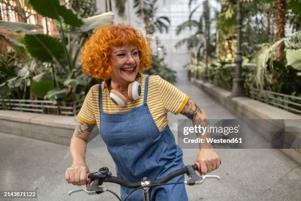 happy redhead senior woman with bicycle on footpath - peto prenda de vestir fotografías e imágenes de stock
