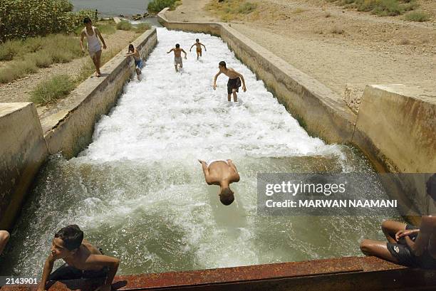 An Iraqi boy falls flat on his face as he plays dead 30 June 2003 in a water canal that flows into the Tigris River in Samara, some 175km north of...