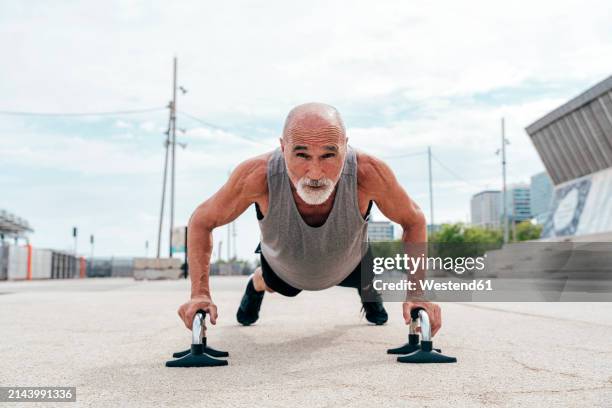 determined senior man doing push-ups on handles - manilla fotografías e imágenes de stock