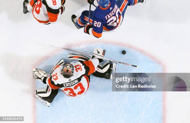 Samuel Ersson and Cam York of the Philadelphia Flyers attempt to stop a shot on goal by Hudson Fasching of the New York Islanders at the Wells Fargo...