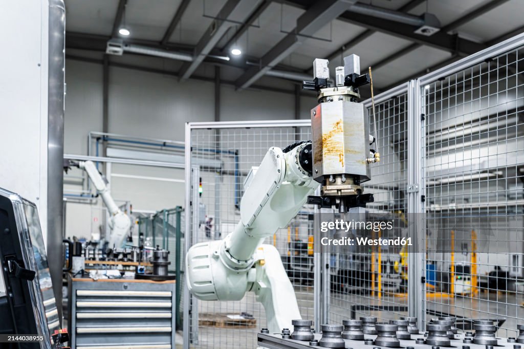 White robotic arm with machinery in modern manufacturing building