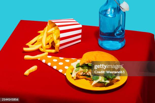 chicken burger and french fries with soda bottle on table against blue background - missing bite stock pictures, royalty-free photos & images