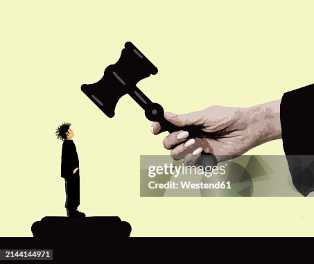 Boy standing under oversized judge's gavel against yellow background Boy standing under oversized judge's gavel against yellow background