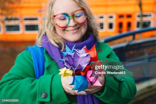 smiling woman holding colorful origami flowers - paper flower stock pictures, royalty-free photos & images