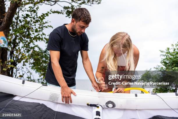 friends preparing a kiteboarding kite with the beach in the background. - fashion suit stock pictures, royalty-free photos & images