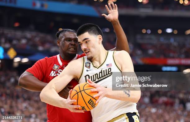 Zach Edey of the Purdue Boilermakers moves the ball against DJ Burns Jr. #30 of the North Carolina State Wolfpack during the first half of the NCAA...